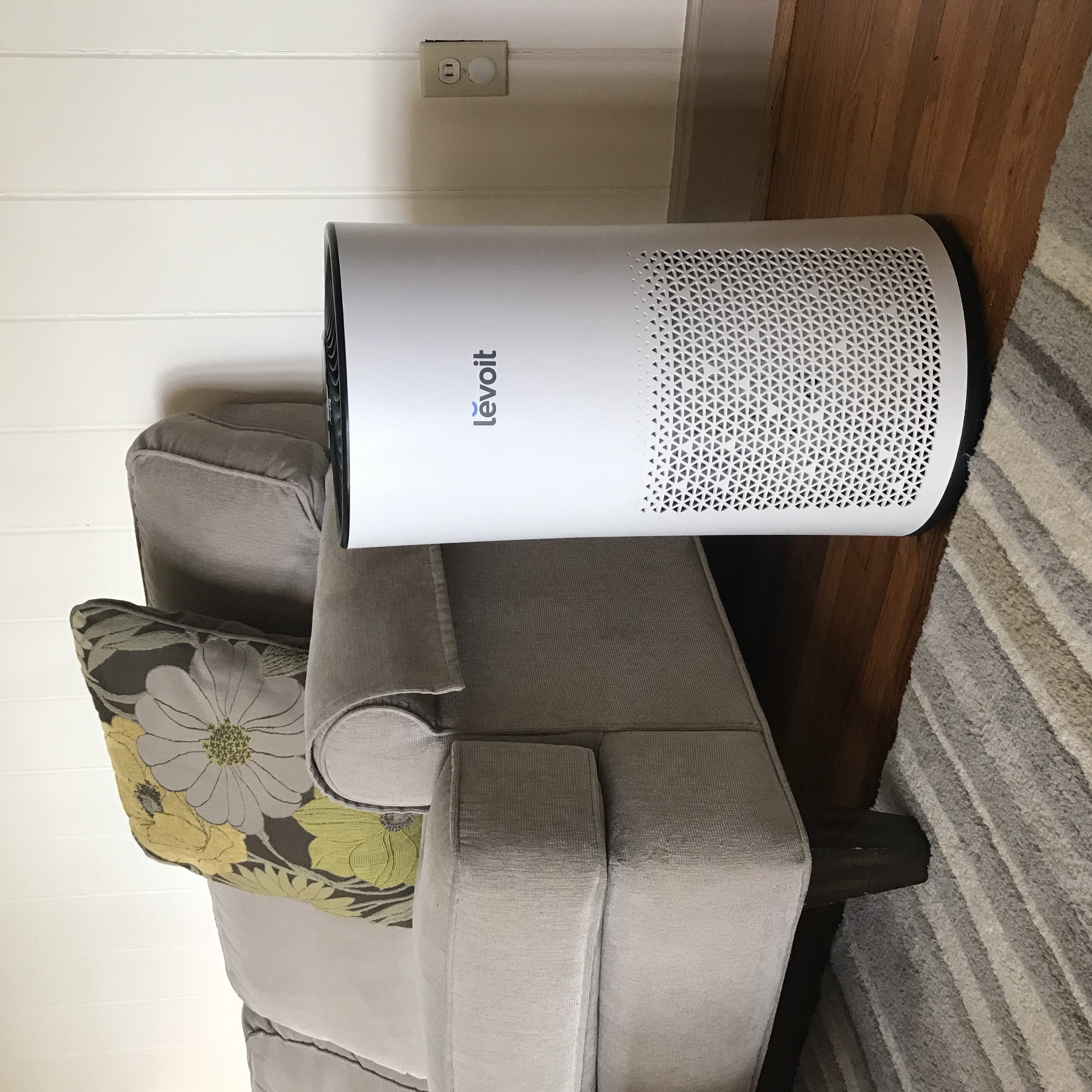 An air purifier in a living room next to a couch. 

”Air Purifier (Levoit LV-H133) (49318571012)” by Home Air Quality Guides is licensed under CC BY-SA 2.0.